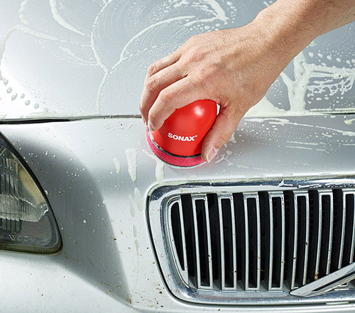 SONAX Clay-ball -puhdistussavi liukuu auton maalipinnalla liukasteen avulla.